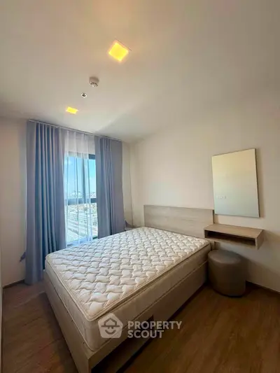 Modern bedroom with large window and stylish furnishings in a high-rise apartment.