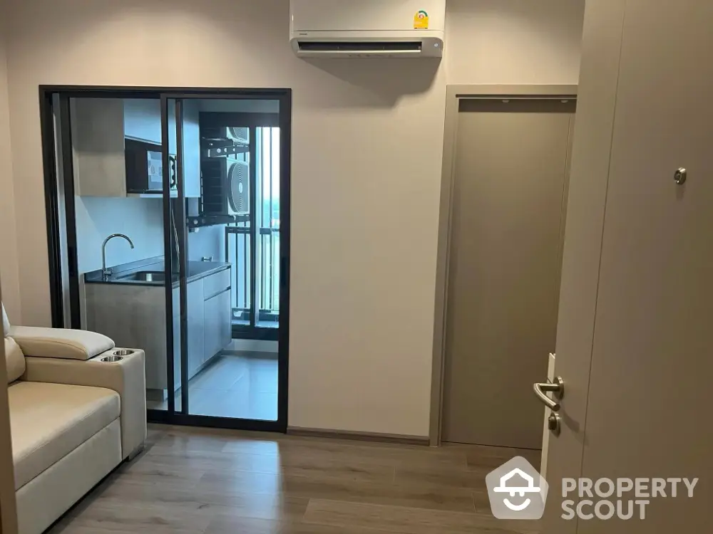 Modern apartment with sleek kitchen and cozy living area, featuring air conditioning and balcony access.