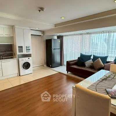 Spacious living room with modern kitchen and city view, featuring a washing machine and fridge.