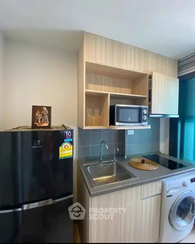Modern compact kitchen with sleek appliances and stylish cabinetry in a cozy apartment.