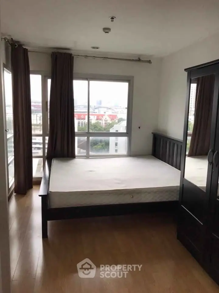 Spacious bedroom with large windows offering city views and ample natural light.