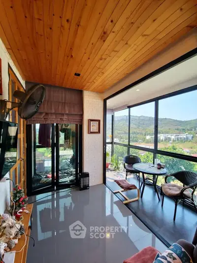 Stunning living room with panoramic mountain views and elegant wooden ceiling.