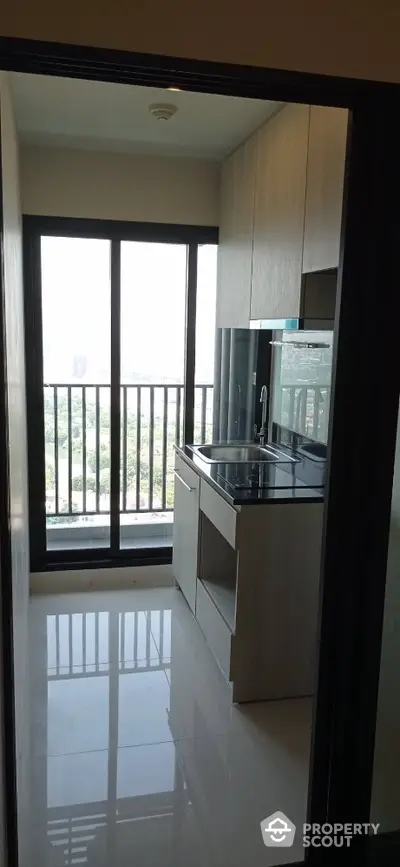 Modern kitchen with sleek cabinetry and large window offering city view