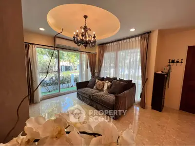 Elegant living room with chandelier and large windows offering garden view