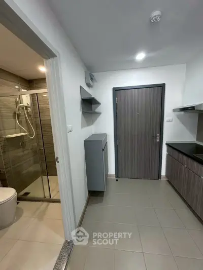 Modern apartment entrance with adjacent bathroom and sleek kitchen area.