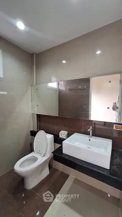 Modern bathroom with sleek fixtures and large mirror in a contemporary apartment.