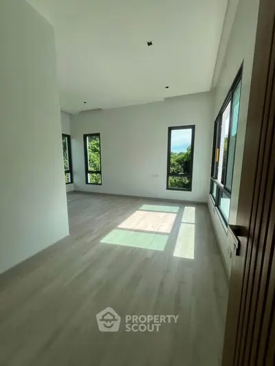 Spacious sunlit room with large windows and scenic views, perfect for modern living.