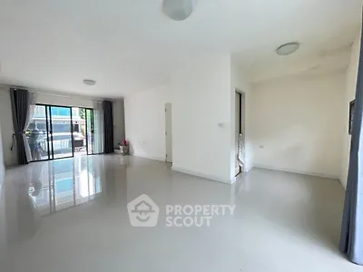 Spacious empty living room with glossy floors and large windows leading to balcony.