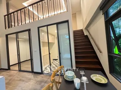 Modern duplex interior with stylish staircase and dining area, featuring large windows and elegant design.
