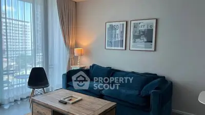 Chic living room with plush blue sofa, elegant decor, and large window offering natural light.