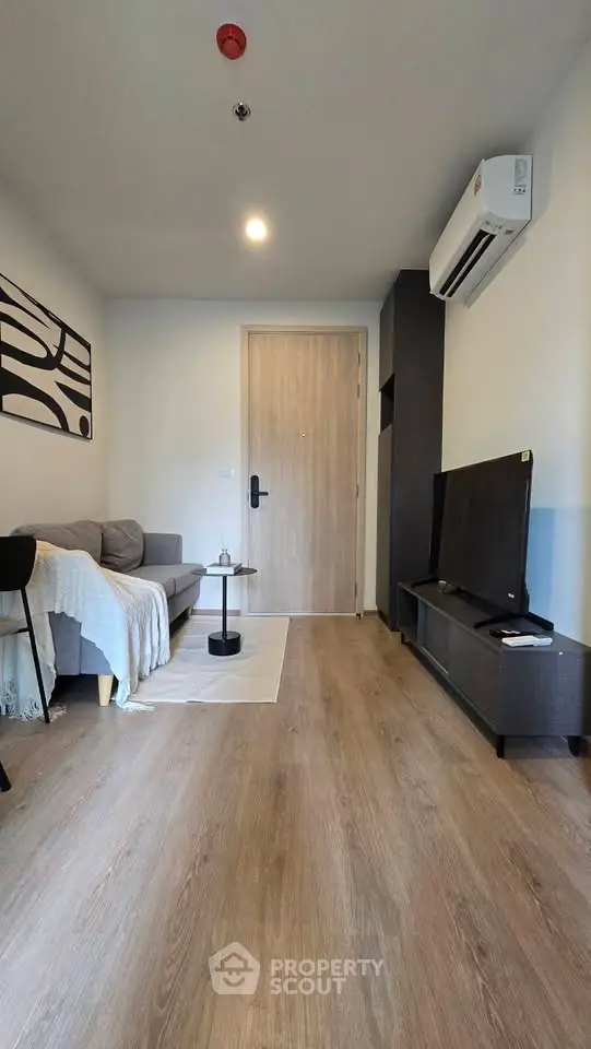 Modern living room with sleek design, featuring a cozy sofa, stylish decor, and a mounted TV for entertainment.