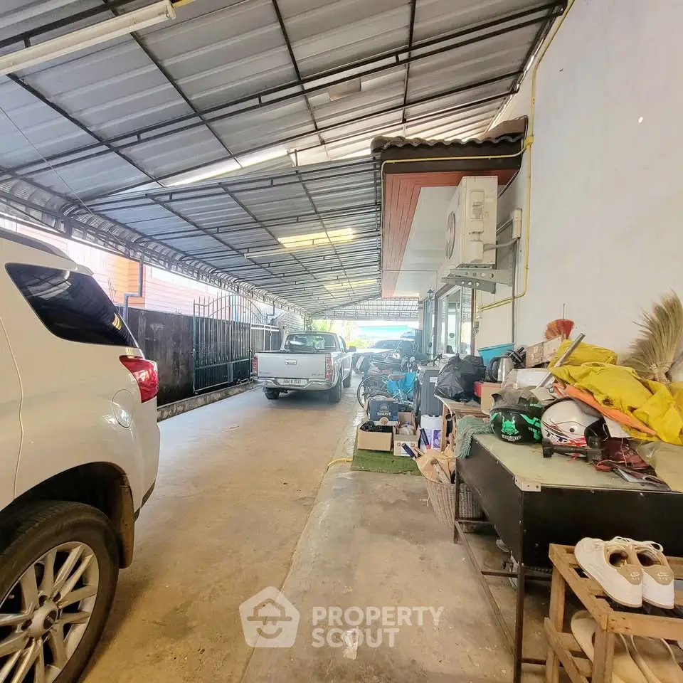 Spacious covered parking area with multiple vehicles and storage space, ideal for residential use.