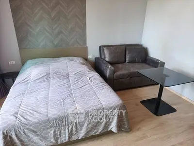 Cozy bedroom with modern decor featuring a comfortable bed, stylish sofa, and sleek glass table.