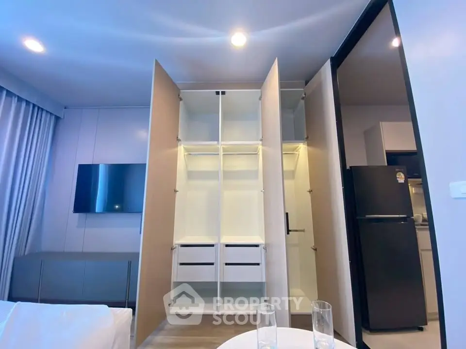 Modern apartment interior with open wardrobe and sleek kitchen appliances