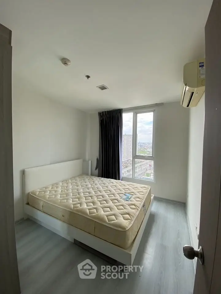 Bright bedroom with large window and city view, featuring a comfortable bed and modern air conditioning.