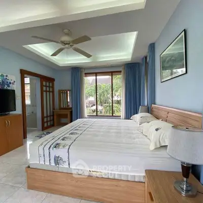 Spacious bedroom with large window and modern ceiling fan in serene setting.