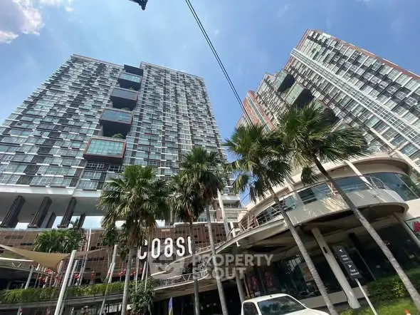 Modern high-rise buildings with palm trees and blue sky in urban setting.