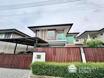 Modern two-story house with sleek design and gated entrance in suburban neighborhood.