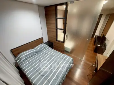 Modern bedroom with wooden flooring and glass partition, featuring a cozy bed and sleek design.