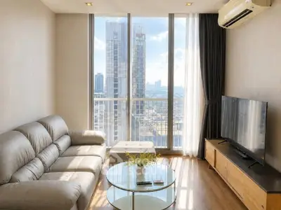 Modern living room with large windows offering stunning city views, featuring a sleek sofa and entertainment center.