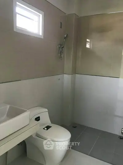 Modern bathroom with sleek design and neutral tones, featuring a shower and contemporary fixtures.