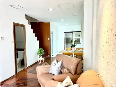 Charming open-plan living room with cozy seating and dining area, featuring modern decor and wooden flooring.