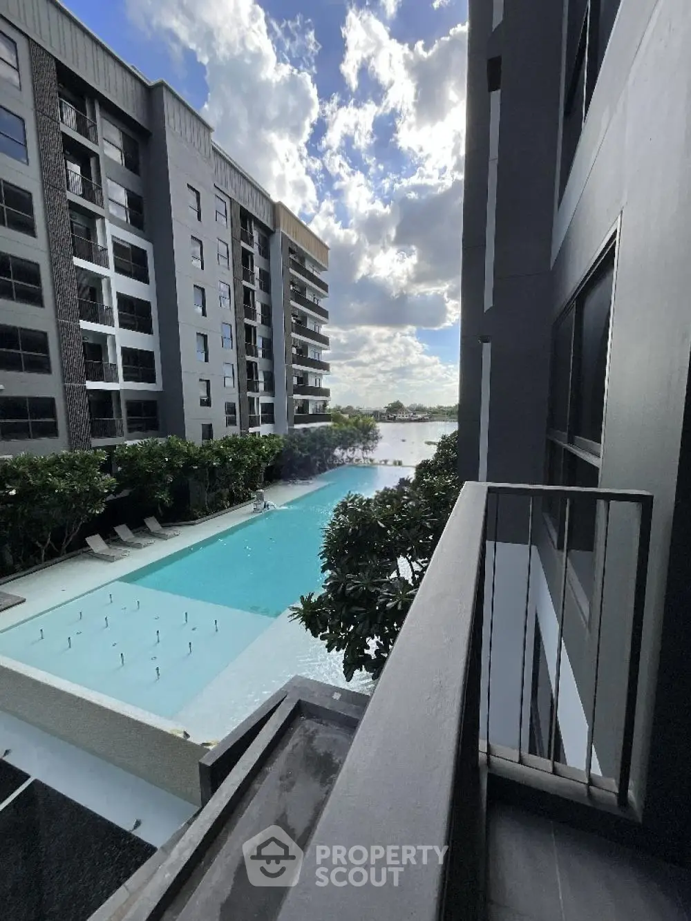 Modern apartment balcony overlooking a luxurious pool with stunning city views.