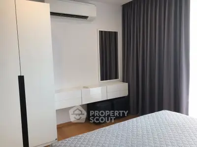 Modern bedroom with sleek furniture and air conditioning, featuring a minimalist design and ample natural light.