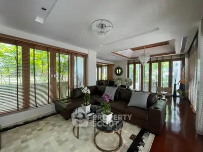 Luxurious living room with elegant decor and large windows offering garden views.