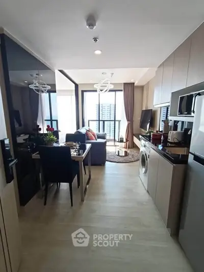 Modern open-plan living room and kitchen with city view, featuring sleek furniture and appliances.