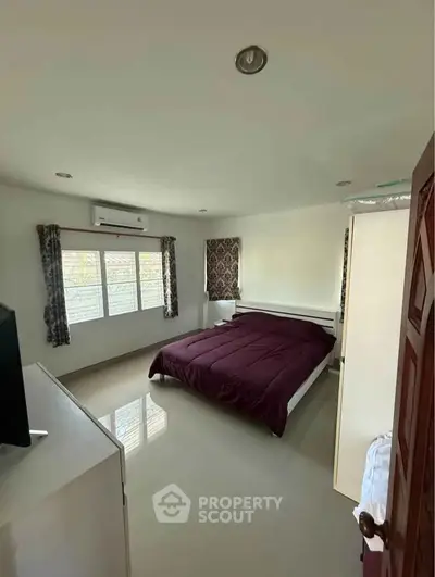Spacious bedroom with modern decor and large windows for natural light.