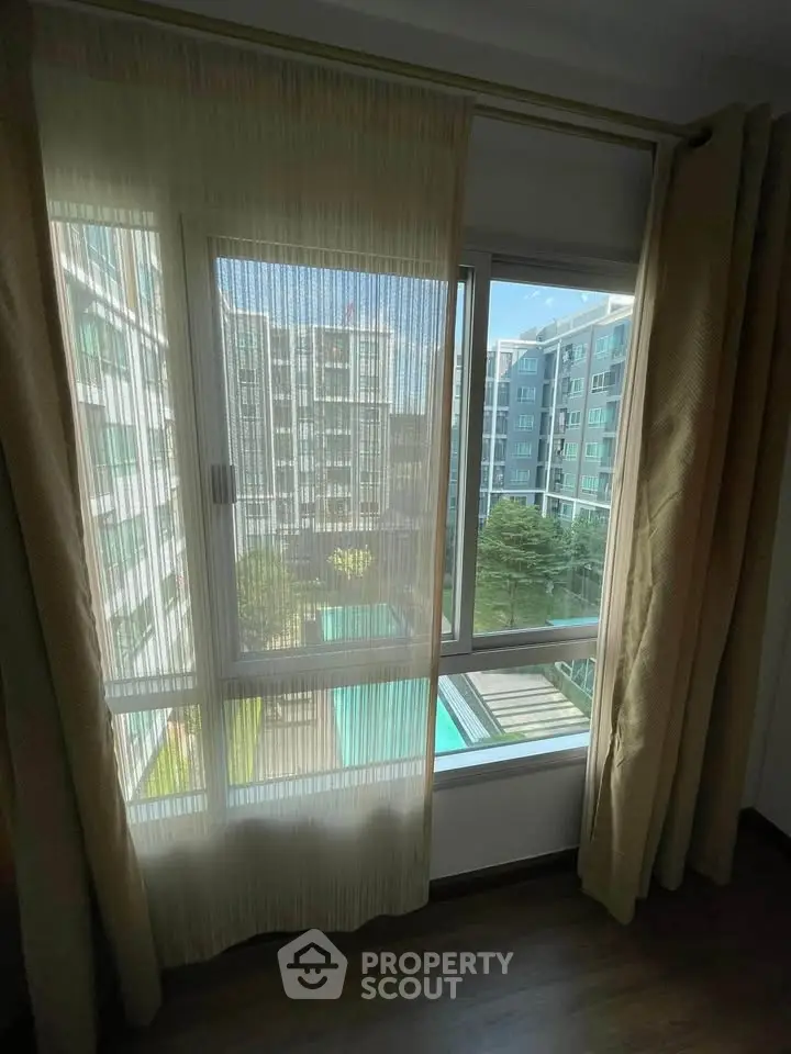 Bright apartment window view overlooking modern residential complex and pool area.