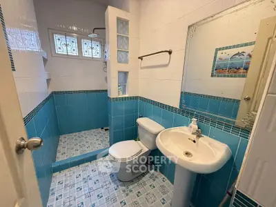 Charming blue-tiled bathroom with shower and modern fixtures, perfect for a cozy home.