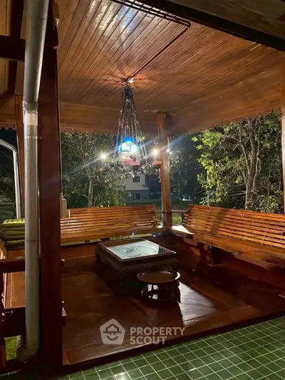 Charming wooden balcony with elegant chandelier and lush garden view