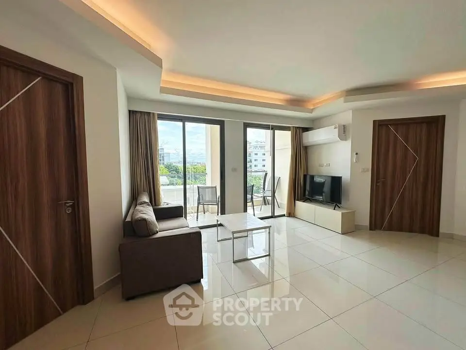 Spacious modern living room with large windows and balcony access, featuring sleek furniture and elegant lighting.
