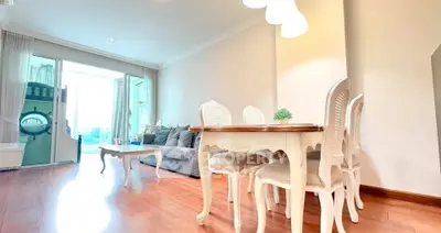 Elegant living room with vintage dining set and cozy sofa, featuring a bright balcony view.