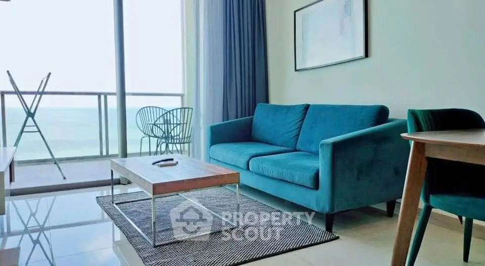 Modern living room with ocean view, stylish blue sofa, and sleek furniture.