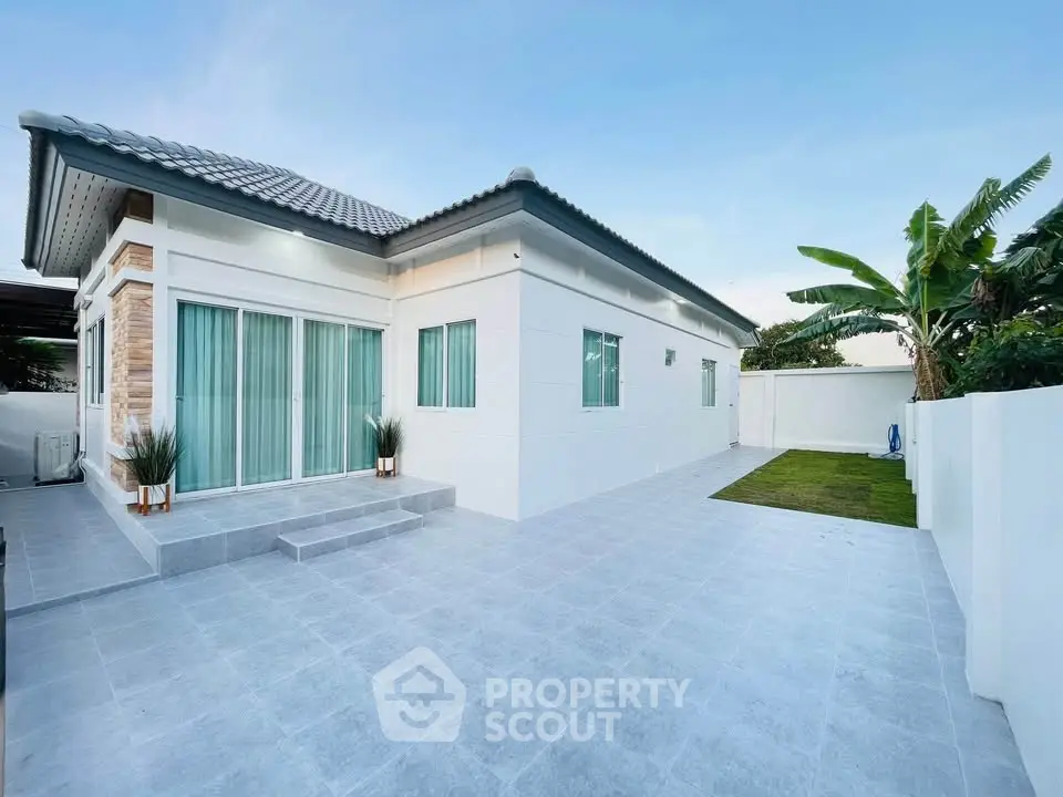Modern single-story home with spacious tiled patio and lush greenery