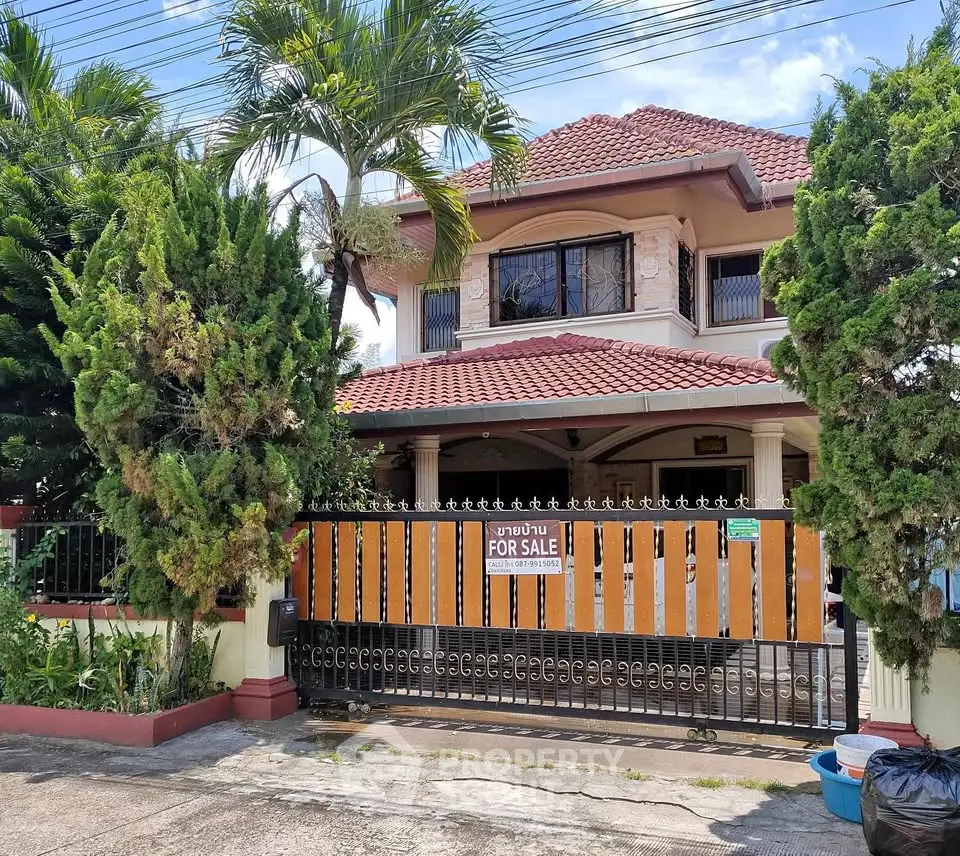 Charming two-story house with lush garden and gated entrance for sale.