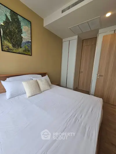 Modern bedroom with stylish decor and cozy ambiance, featuring a large bed and elegant artwork.