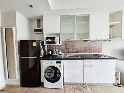 Modern kitchen with sleek appliances, washing machine, and stylish cabinetry in a compact layout.