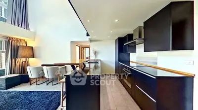 Modern open-layout kitchen with sleek black cabinets and spacious dining area in luxury apartment.