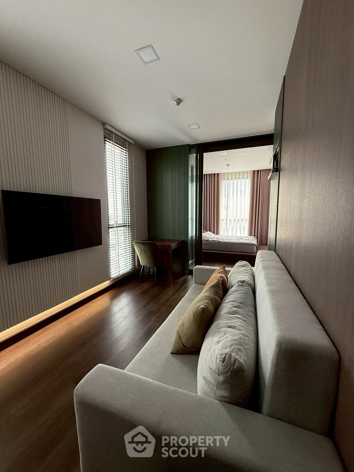 Modern living room with sleek design and natural light, featuring a cozy sofa and wall-mounted TV.
