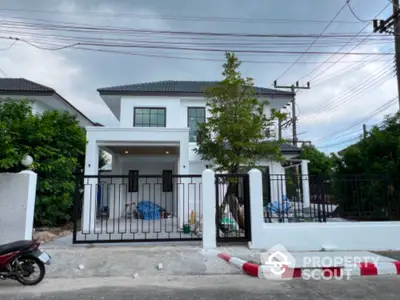 Modern two-story house with gated entrance and lush greenery