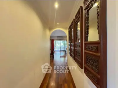 Elegant hallway with wooden flooring leading to a bright living area with balcony view.