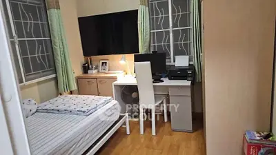 Cozy bedroom with study area, featuring a bed, desk, and large TV, ideal for compact living.