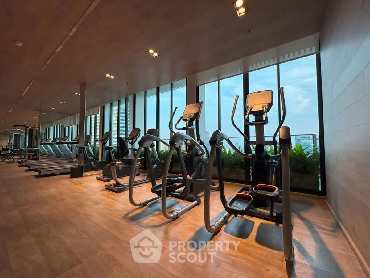 Spacious gym with modern equipment and large windows offering a scenic view.