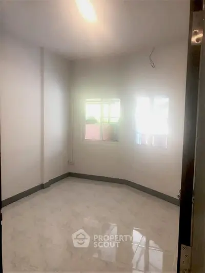 Bright empty room with marble flooring and large windows, perfect for customization.