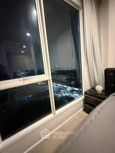 Luxurious bedroom with stunning city view through large window at night.