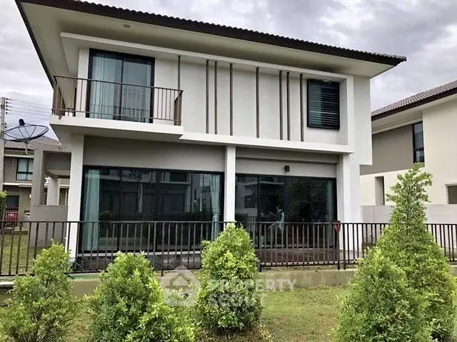 Modern two-story house with balcony and lush garden